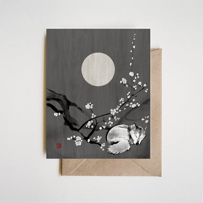 Greeting card with a sleeping fox and cherry blossoms under a full moon on a gray background.